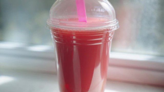 A Red-Colored Bubble Tea With Pink Straw Placed Beside The Window. -medium shot