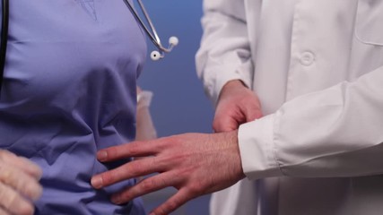Male medical professional doctor in a lab coat being a pervert, trying to hit on a nurse in scrubs , and a stethoscope at work, by touching her gloved hands, and she is rejecting him multiple times. - Powered by Adobe