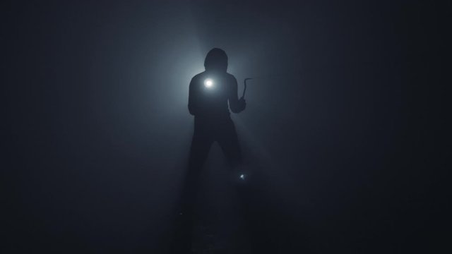 A thief with a flashlight and a crowbar