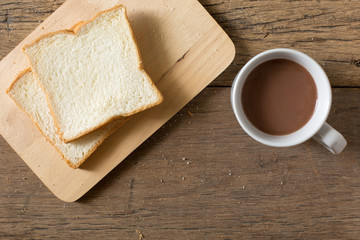 Top view of Breakfast bread and coffee in a white cup on a wooden table with morning sunlight and  copy space