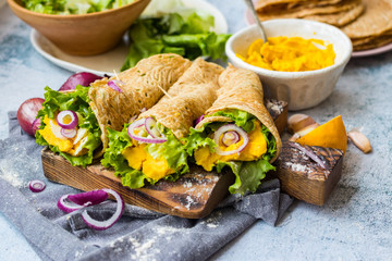 Vegan healthy Mexican tortilla flatbread wraps stuffed with green salad leaves, onion and chickpea hummus filling. Vegetarian food appetizer. Homemade