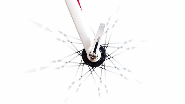 A center of front wheel of the bicycle rotates quickly on a white background. Detail of road bike while rotates, close up.