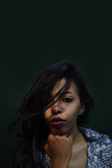 Fototapeta premium young African woman posing at studio, face with hand portrait over dark background 