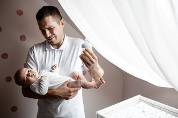 Father and little kid in the nursery. The first year of life. Uncertainty and fear of a child....