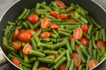 Green beans and grape tomatoes sauteed with olive oil in frying pan