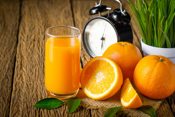 Close-up of Glass squeezed orange juice and fresh fruits ripe cut half, slice with green leaves on old wood vintage table. Breakfast food or beverage for the morning. Concept organic healthy natural.