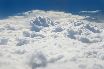 View of puffy white cumulus clouds from above with a blue sky