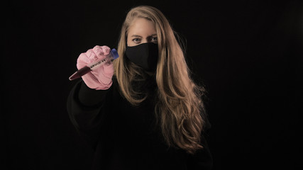 Girl in a black mask holds a test tube with blood and the inscription covid-19. Isolated on black background. Health care and medical concept. Coronavirus Epidemic