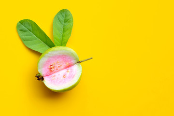 Top view of fresh ripe guava with leaf on yellow background.