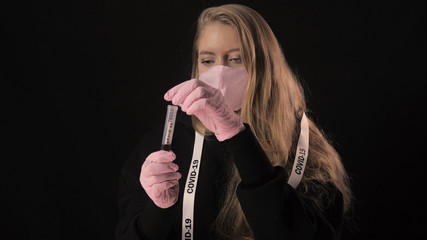 Girl holds opens a test tube with blood and the inscription covid 19 and drinks it. Isolated on black background. Health care and medical concept. Close up portrait . 4k. Coronavirus Epidemic