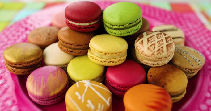 Many french macarons selection of colorful pastries on pink dessert plate. Retro vintage home kitchen background. Assortment of fancy pastry macaroons tasting.