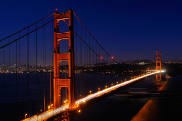 Fototapeta na wymiar Golden Gate Bridge and San Francisco skyline at night with passing ocean cargo ship