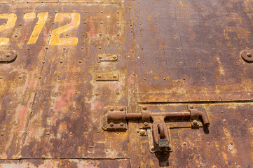 Old weathered bolt with lock on it and dated rusty factory gate in the background in the sunlight