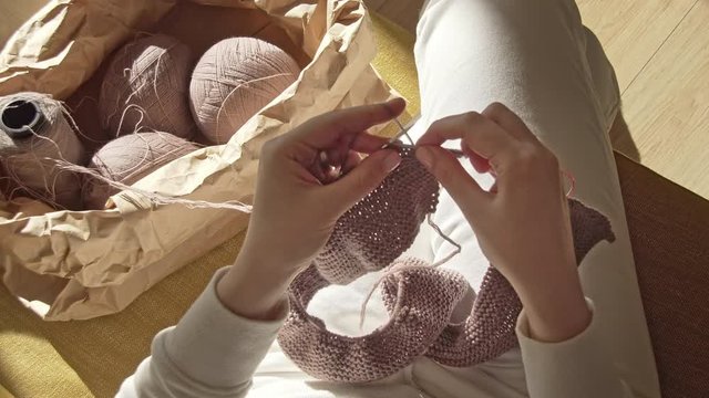 Womans hands knitting needles from the package of balls of yarn on a sunny day view from above