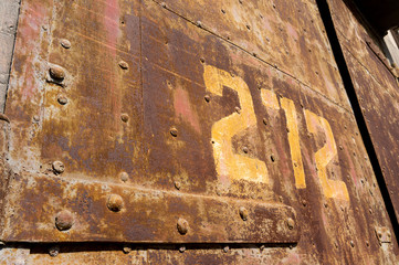 Old weathered rusty factory gate with number in the sunlight