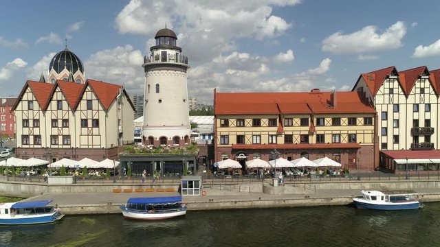 Famous fish fishing village lighthouse. Russia Kaliningrad cityscape new tourist quarter center western. River Pregoli. German medieval cityscape. Sunny day summer. Travel landmark. Aerial drift 4K