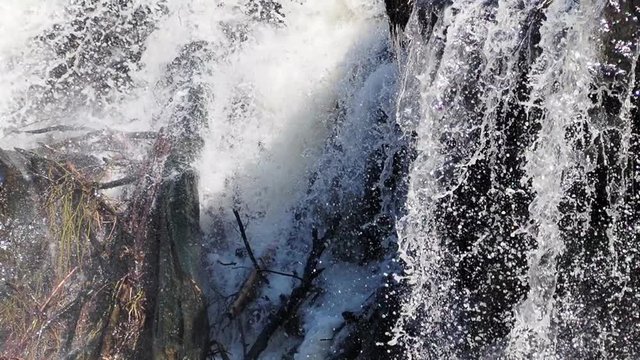 close up shot of a rapid stream of water hitting a rock and creating a splash. Nature in Estonia. Very Strong raging river.