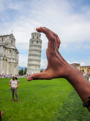 A shot of tourist hand measuring the leaning tower of Pisa