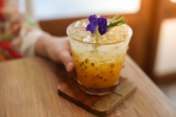 Passion fruit juice iced in a glass on wooden table in cafe.