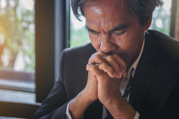 Close up of Senior businessman is disappointed and seriously by business results report. Pray for crisis economic concept