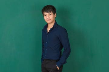 Young Asian man standing at green wall.