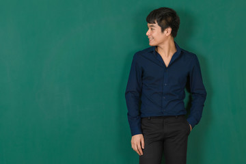Young Asian man standing at green wall.