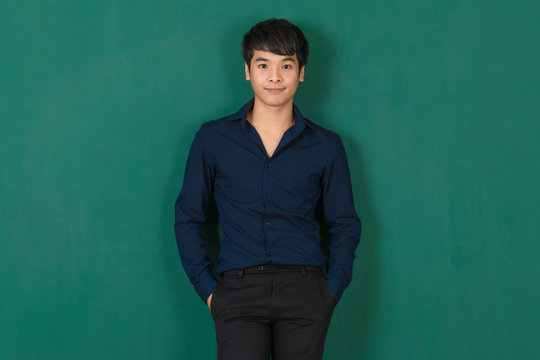 Young Asian man standing at green wall.