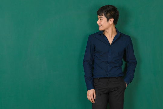 Young Asian man standing at green wall.