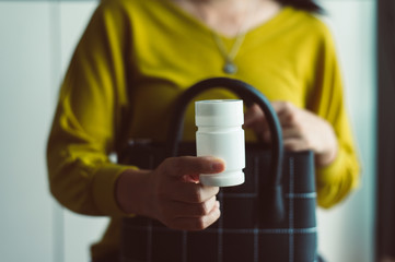 Hands woman holding a medicine pills bottle into handbag,Healthy and lifestyle concept