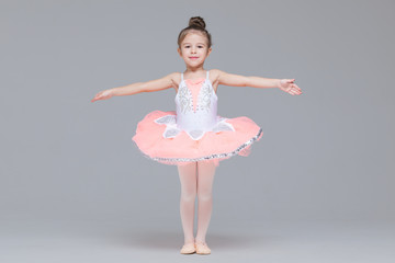Cute adorable ballerina little girl in pink tutu dance practices ballet dancing