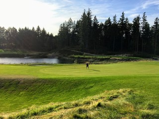 A man alone on a putting green playing golf surrounded by beautiful scenery outside of Victoria,...