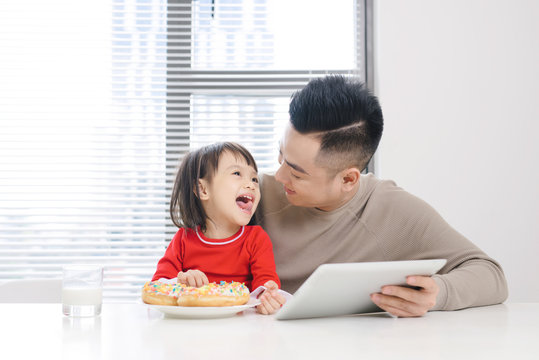 Young Dad And His Daughter Eating Pizza And Using Ipad.