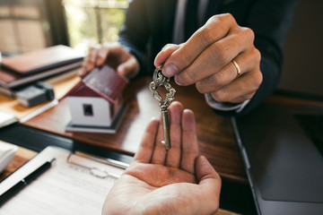 Salesman house brokers provide key to new homeowners in office.