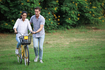 Couple love resting or relaxing in a green park, hugging action and looking forward and ride on back for romantic date or vacation in valentine day