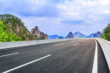 Empty asphalt road and mountain with sky on cloudy day.