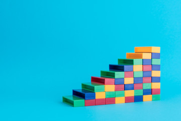 Color plastic block stacking as stair on blue background with copy space. Concept of business and financial strategy, planning for success growth KPI target.