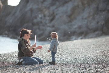 Happy pretty girl and mom walk along the sea coast against the background of the sea, from behind a beautiful landscape