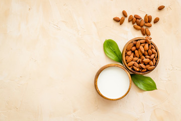 Almond milk near nuts on beige background top-down copy space