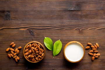 Almond milk near nuts on wooden background top-down copy space