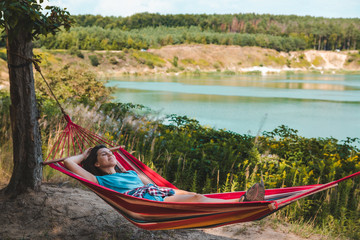 woman laying on hammock enjoying the view of summer lake