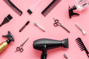 Professional hairdressing set with combs and hairdryer on pink background top-down