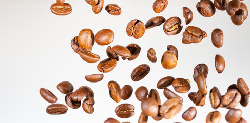 Falling coffee beans, in motion, on a white background. Selective focus.