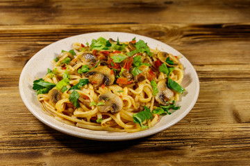 Pasta with mushrooms and tomato sauce on wooden table