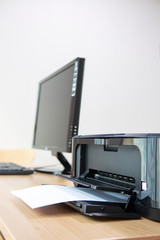 사무실 책상 위에 프린터와 a4용지 컴퓨터