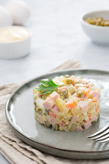 Russian salad Olivier with mayonnaise and egg served in culinary ring on plate. Light background.