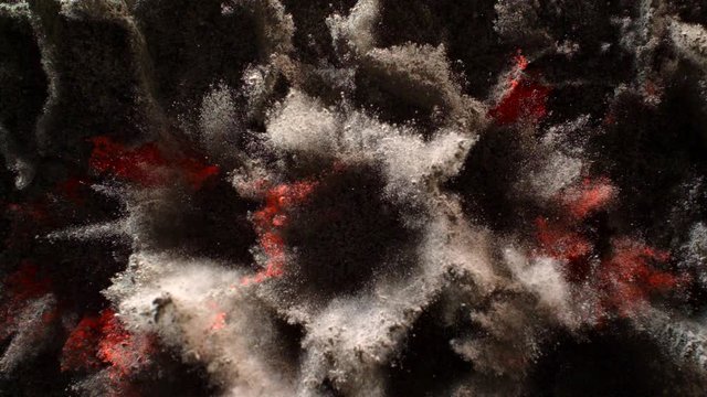 In real slow motion footage, lumps of grey powder interspersed with bright red powder burst simultaneously with individual charges, making honeycomb formation before overwhelming the camera. Top Shot