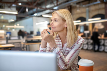 Blonde woman sitting at laptop, considering new idea