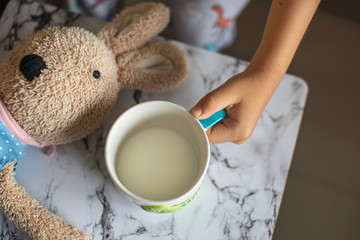 Child's hand holding a mug of milk.