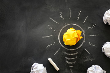 Education concept image. Creative idea and innovation. Crumpled paper as light bulb metaphor over blackboard