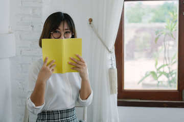 Beautiful women wearing a white shirt,Holding a yellow book In a coffee shop